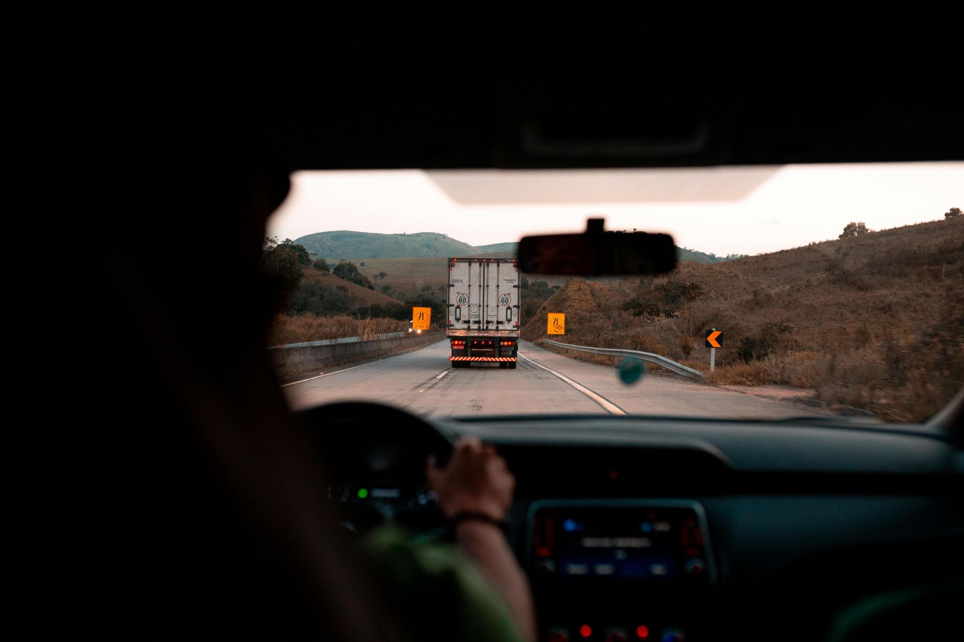 Scenic drive with a truck on a highway surrounded by hills. Perfect for travel themes.